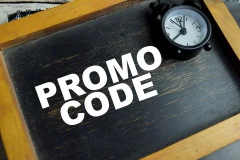 Chalkboard with phrase promo code and school supplies on wooden desk Foto stock