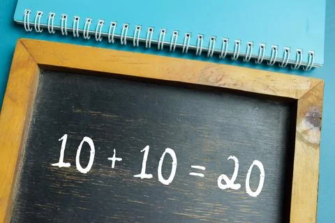 Chalkboard with phrase simple 10+10=20 math equation on wooden desk. Stock Photos