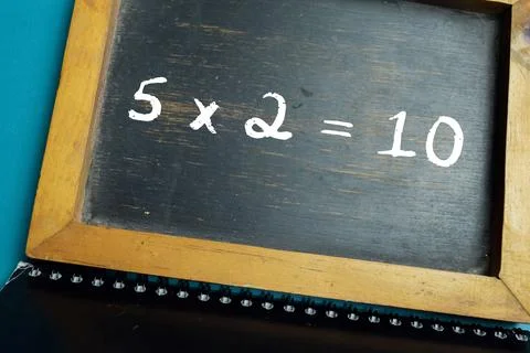 Chalkboard with phrase simple 5x2=10 math equation on wooden desk. Stock Photos
