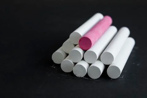 Chalks and red one in stacked on chalk dusty black background Stock Photos
