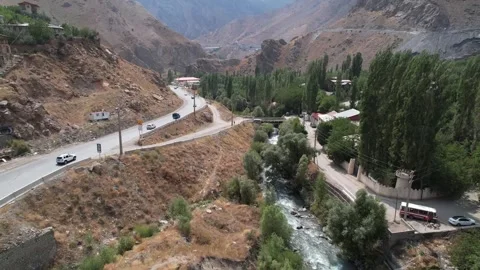 Chalus Road highway runs beside a river and poplar line through a dry mountain Stock Footage 343907285