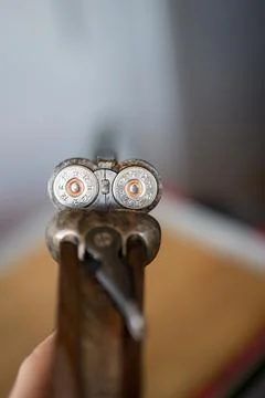 Chamber of an open parallel 12 gauge shotgun on a wooden table. It's loaded Stock-Fotos