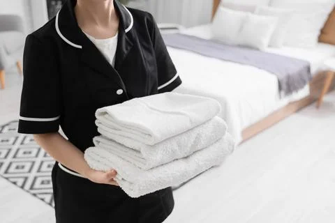 Chambermaid with stack of soft towels in hotel room Stock Photos