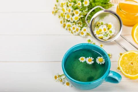 Chamomile tea in a white cup on texture background. Stock Photos