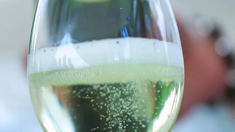 Champagne with bubbles and foam is poured into a transparent glass goblet, close Stock Footage 266393914