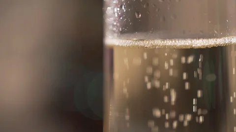 Champagne bubbles in a glass on the background of a blinking festive garland Stock Footage 127750516