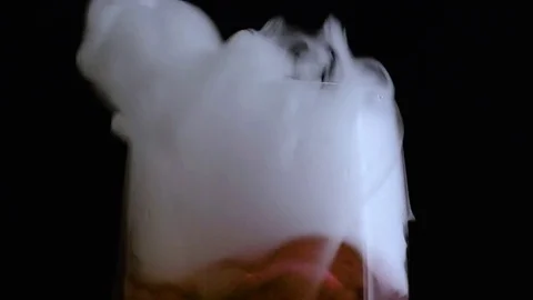 Champagne flute with red liquid bubbling and smoking in macro Stock Footage 70674715