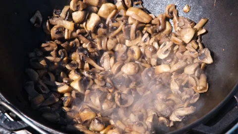 Champignons are fried in a cauldron outdoors. Mushrooms are fried. Frying Stock Footage 280213916