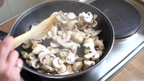 Champingnons being salted and mixed in the pan Stock Footage 79722414