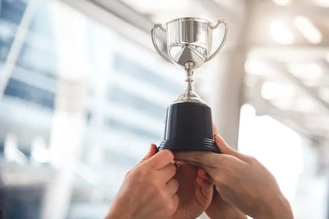 Champion silver trophy for runner up winner with sport player hands in spor.. Stock Photos