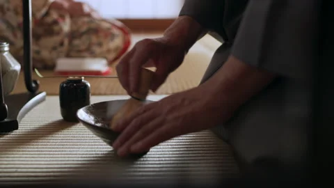 Champion tea master using a bamboo matcha tea whisk to whisk the powder with hot Stock Footage 199460670