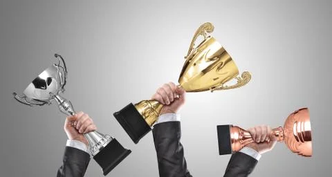Champions holding golden, silver and bronze cup trophies Stock Photos