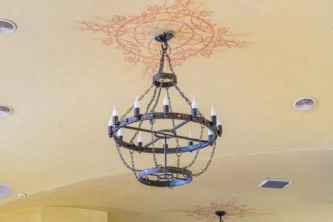 Chandelier with multiple arms, circular light pattern on floral ceiling desig Stock Photos