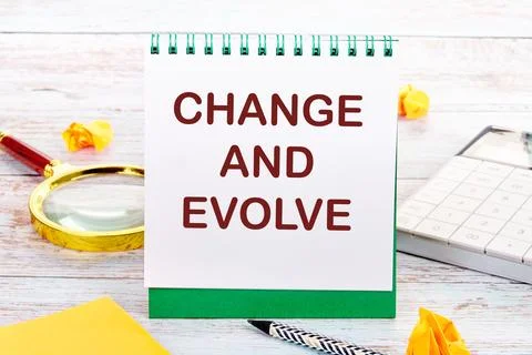 CHANGE AND EVOLVE text on the white sheet of the notebook is next to a magn.. Stock Photos
