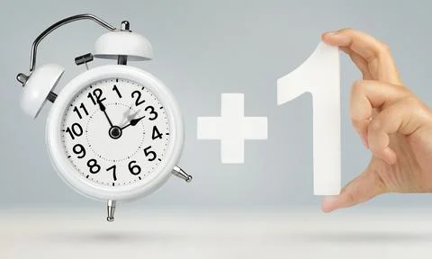 Change time. Spring forward, on a gray background. A white alarm clock indicates Stock Photos