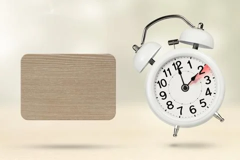 Change time. Winter time concept, on a wooden background. A white alarm clock Stock Photos