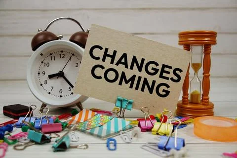 Changes Coming text on paper card with alarm clock and stationary on wooden.. Stock Photos