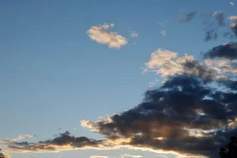 Changing cloudscape at sunset. Blue, yellow and grey colours Stock Photos