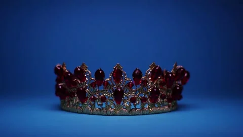 Changing light shows gold tiara with red gemstones on blue Stock Footage 137455037