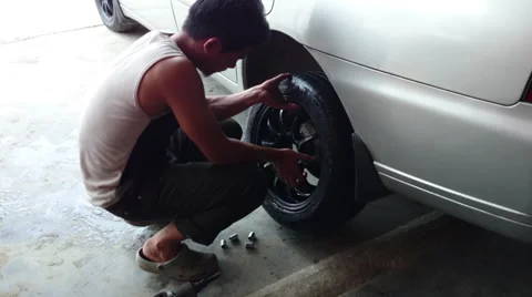 Changing tyre: Man attaching new wheel lug nuts to a new tyre Stock Footage 39218828