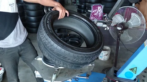 Changing tyre: Man placing new tyre on a tyre changing machine in a garage Stock Footage 39198057