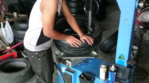 Changing tyre: Man placing a new tyre on a wheel rim using machine and pry bar Stock Footage 39208985