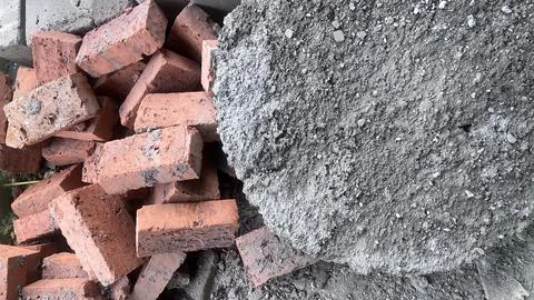 A chaotic mix of red bricks and a large mound of gray concrete rubble on a co Foto stock