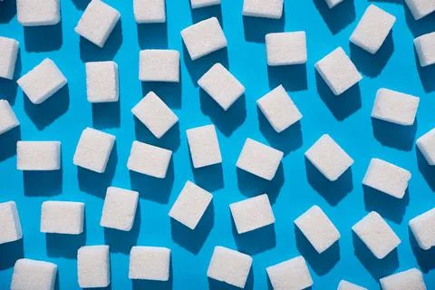 Chaotic sugar cubes pattern on blue background. Abstract, minimal style. Stock Photos