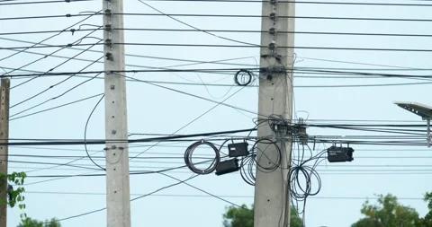 Chaotic tangle of communication cables and power lines on concrete utility 库存影片 348893078