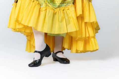 Character dancer feet in black dance shoes and yellow skirt close up on whi.. Stock Photos