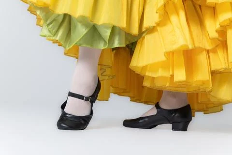 Character dancer feet in black dance shoes and yellow skirt close up on whi.. Stock Photos
