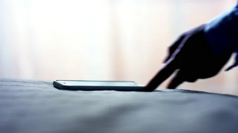 Character puts smartphone in case on blanket near body Stock Footage 238767252