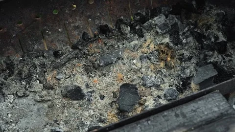 Charcoal ashes fill a grill after cooking has concluded. The remnants include 库存影片 344670747