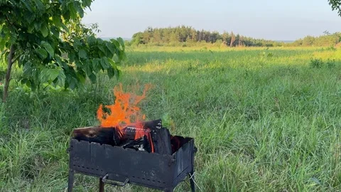 Charcoal barbecue grill with burning fire standing outdoors in green meadow Stock Footage 345179381