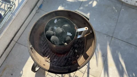 Charcoal chimney starter getting hot on a barbecue grill Stock Footage 306076997