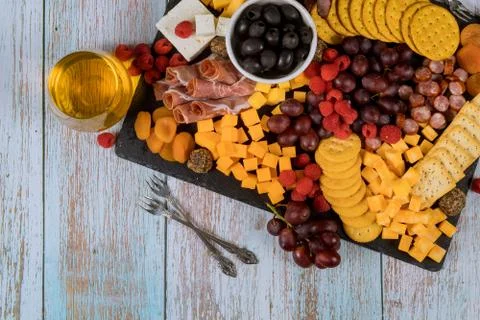 Charcuterie board with cheese, grape, raspberry, crackers and drink. Stock Photos
