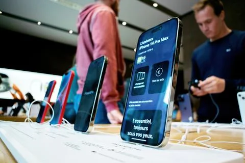 Charging Apple iPhone 14 Pro against a Apple Store background wi Stock Photos