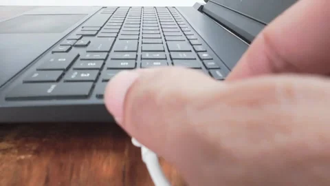 Charging Black Laptop Computer with White Cable on Wooden Desk Stock Footage 311796406