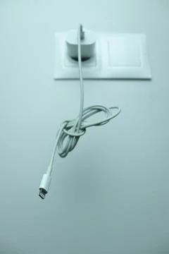 Charging cable hanging from wall socket Stock Photos