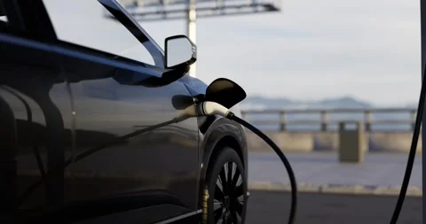 Charging cable plugged into a electric vehicle at an outdoor charging station Video stock 332301985