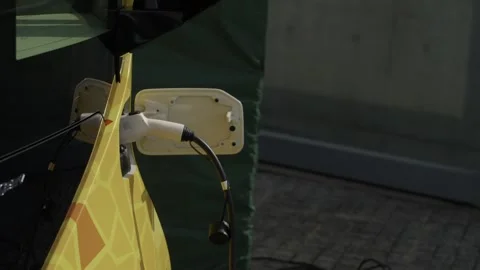 Charging Cable Plugged into Yellow Electric Car Charging Port Close Up Stock Footage 343987498
