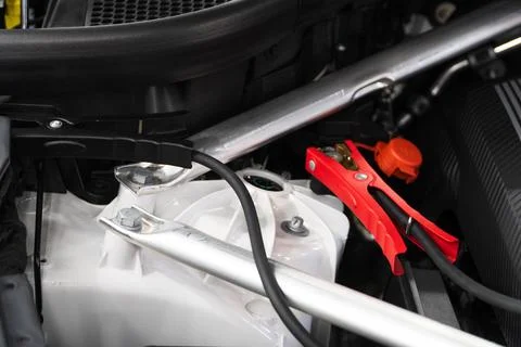 Charging car battery with electricity using connecting cables. Stock Photos