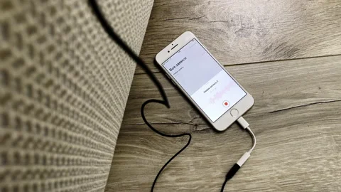 Charging cellphone with open audio record appliance on table Video stock 164353922