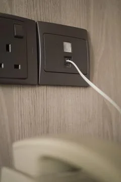 Charging device plugged into wall socket in modern setting Stock Photos