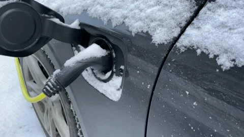 Charging electric car in the winter when it is snowing outside Stock Footage 226230312