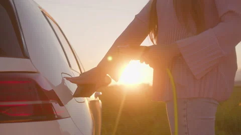 Charging EV car near a highway at sunset Stock Footage 158900275