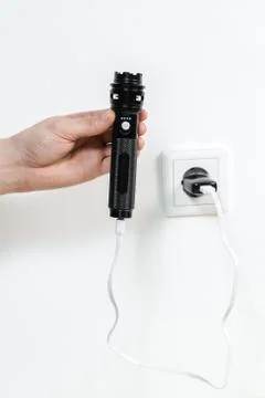 Charging the flashlight from the wall outlet on a white background Stock Photos
