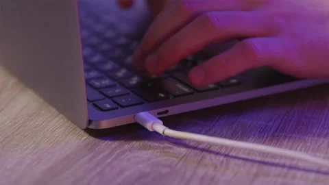 Charging laptop via USB-C from power station while typing Stock Footage 334732356