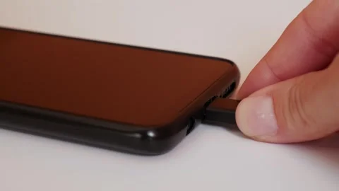 Charging a mobile device with a cable. Close-up of hands and USB port. Stock Footage 306179970