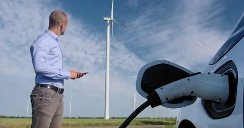 Charging plug charges car and man with phone stands nearby Stock Footage 160222389